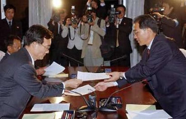 South Korean Vice Unification Minister Rhee Bong-jo (L) and North Korean head of delegation Kim Man-gil exchange a joint statement at the senior inter-Korean talks in North Korean city of Kaesong May 19, 2005.